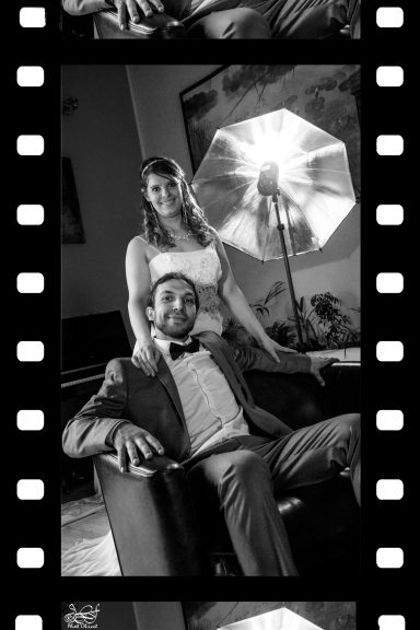 Couple posant ensemble, homme en costard et femme en robe blanche, avec un éclairage de studio.