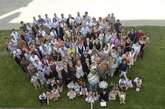 Groupe de personnes réunies en extérieur, souriantes, vêtues de tenue de fête.